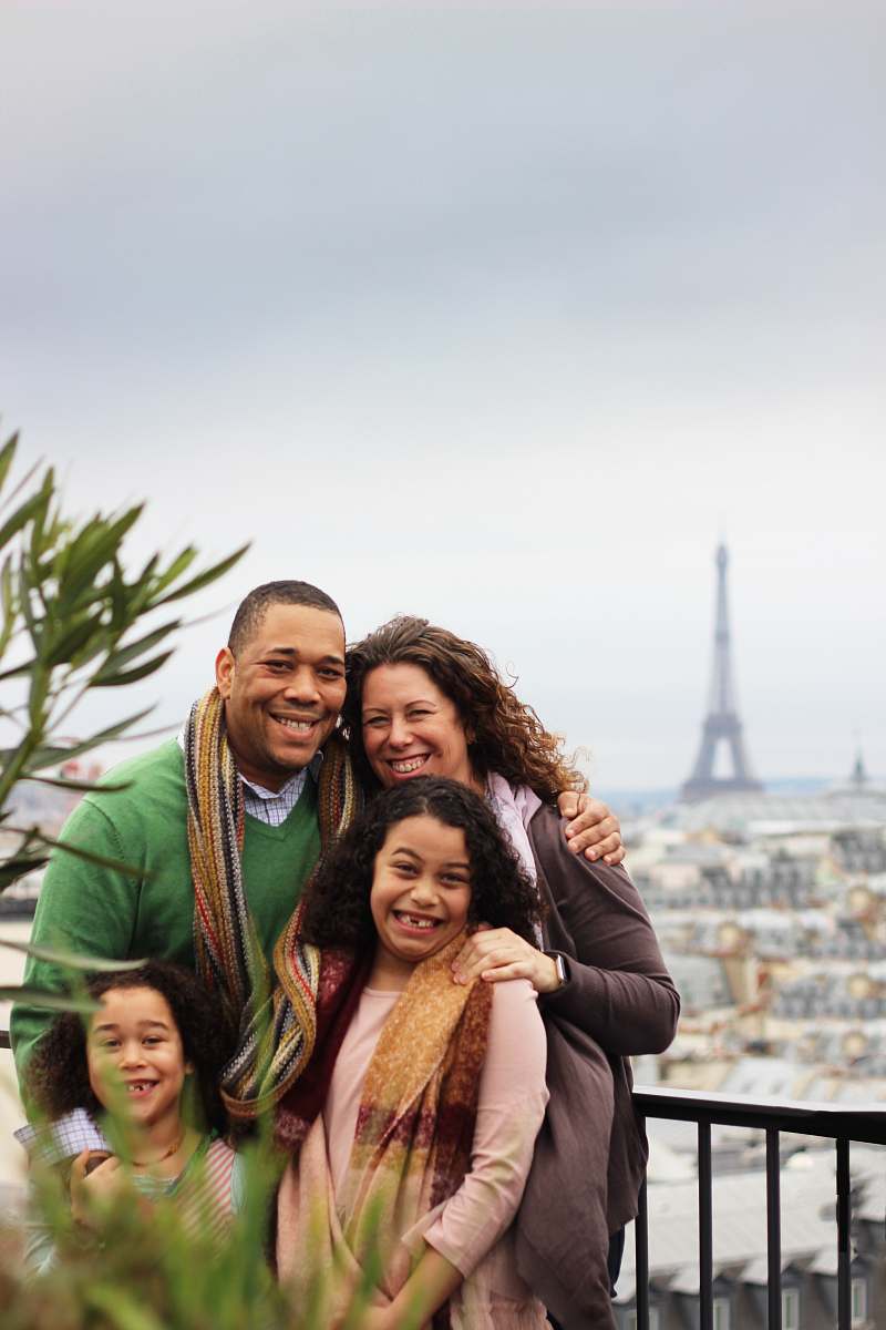 person woman in black long sleeve shirt carrying girl in brown scarf family