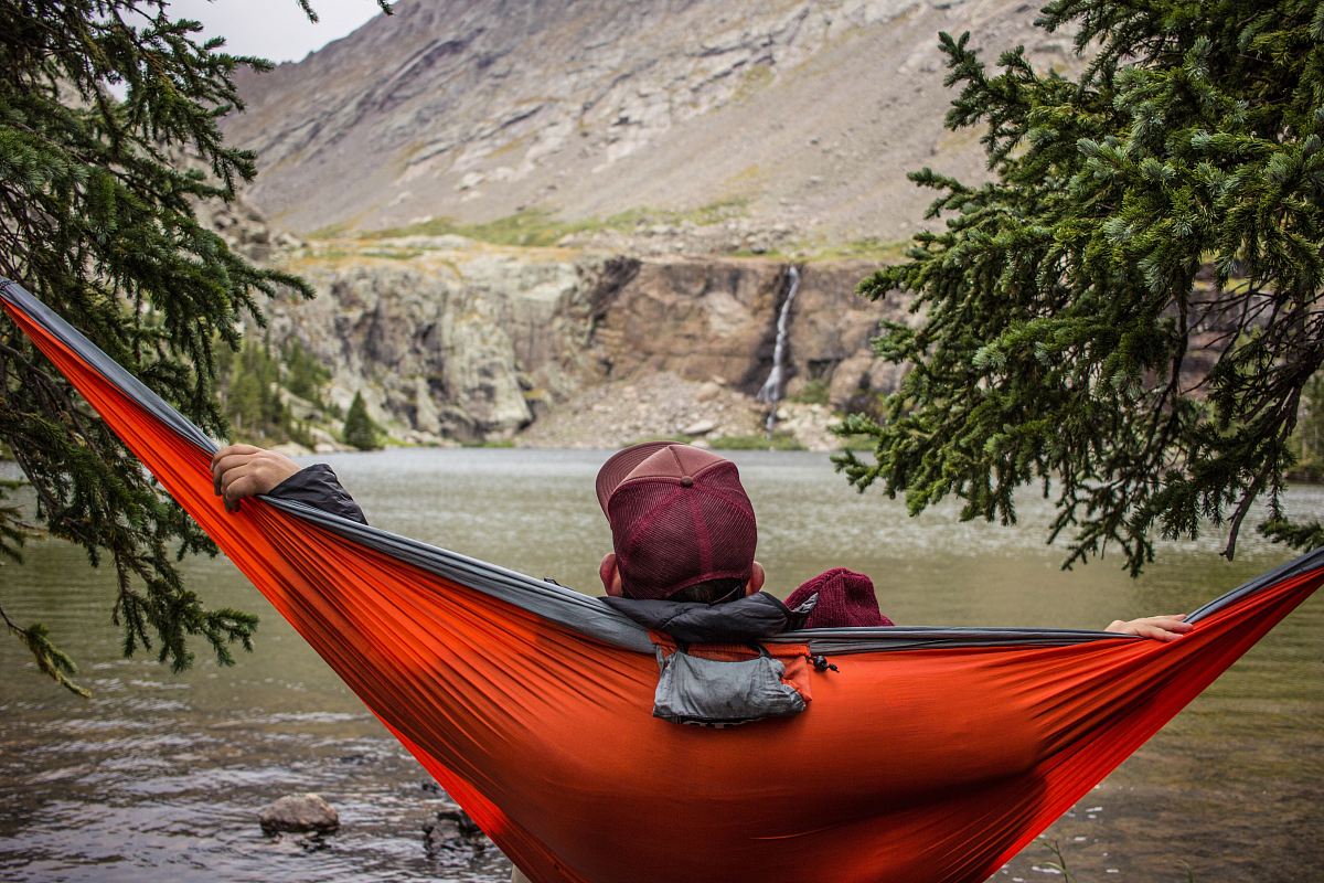 man lying on hammock beside trees