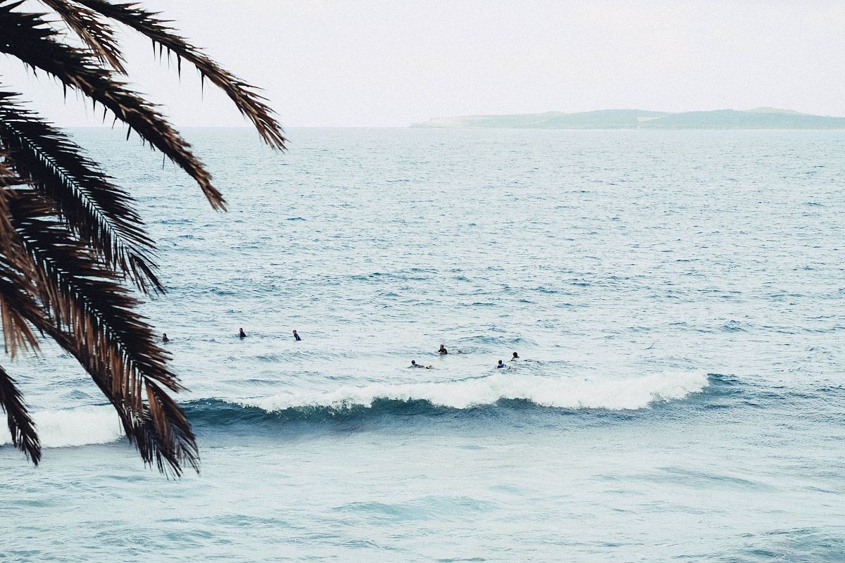 people swimming on sea during daytime
