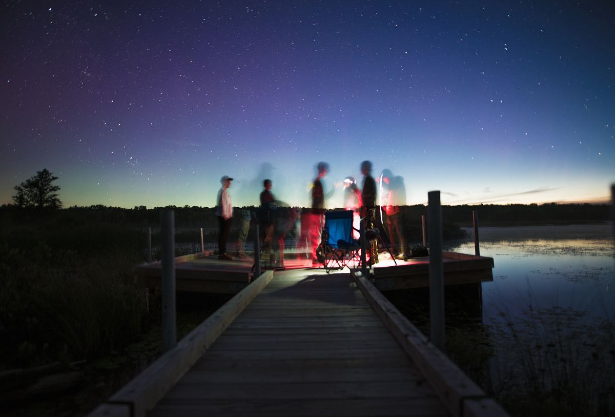 person illustration on brown wooden dock stage photography during nightime