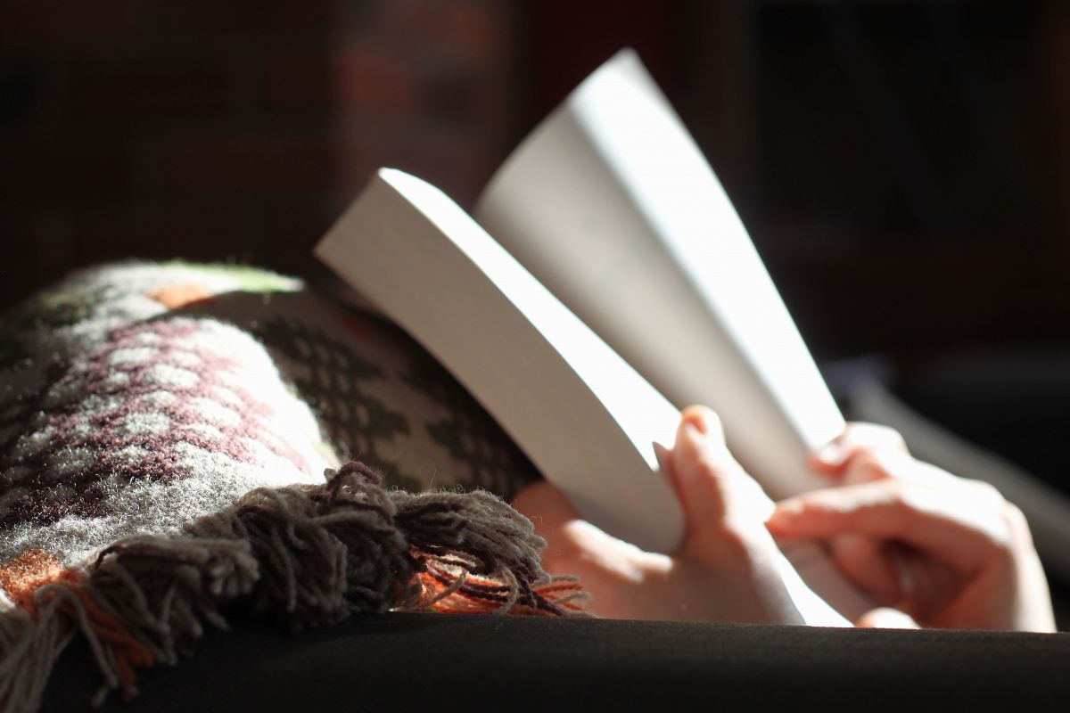 photo of person holding book near textile