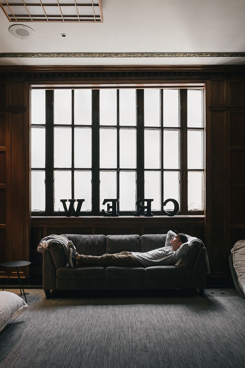 photo of person laying on sofa near window