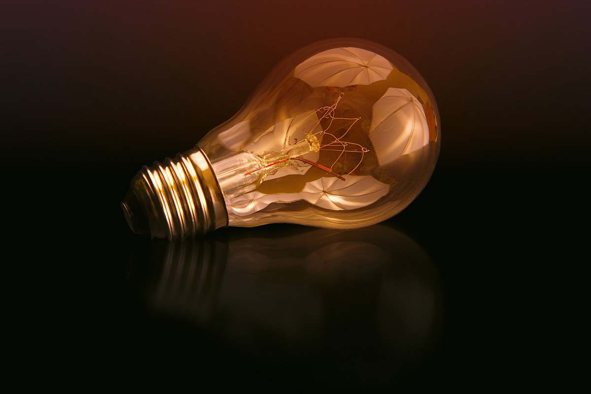 lightbulb incandescent bulb on black surface reflection