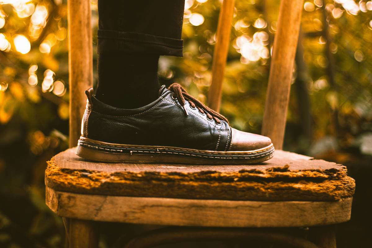 bokeh person wearing black dress shoe stepping on chair worship