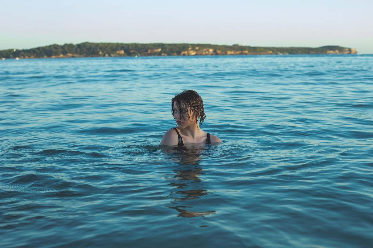 swimming photography of woman in black swimming wear soaked in sea people