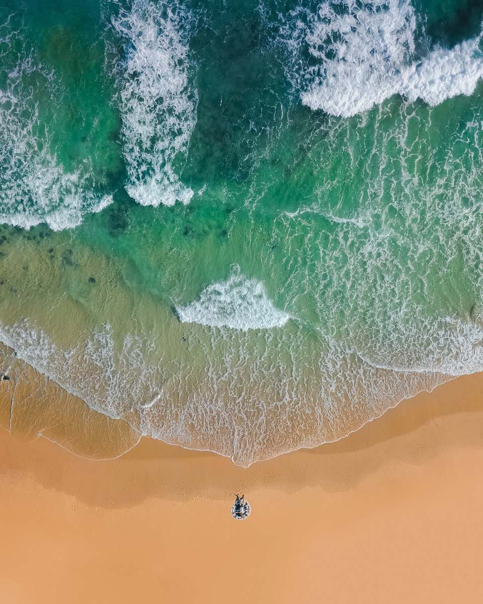 water top view photography of brown sand on beach with teal ocean water during daytime ocean