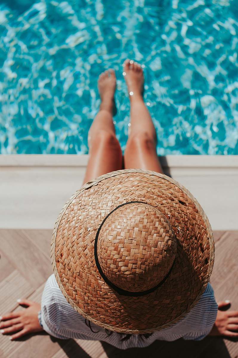 people woman sitting on poolside setting both of her feet on pool woman