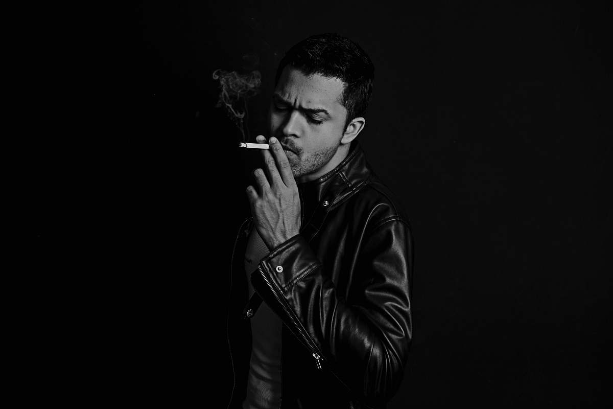 person grayscale photo of man smoking cigarette smoking