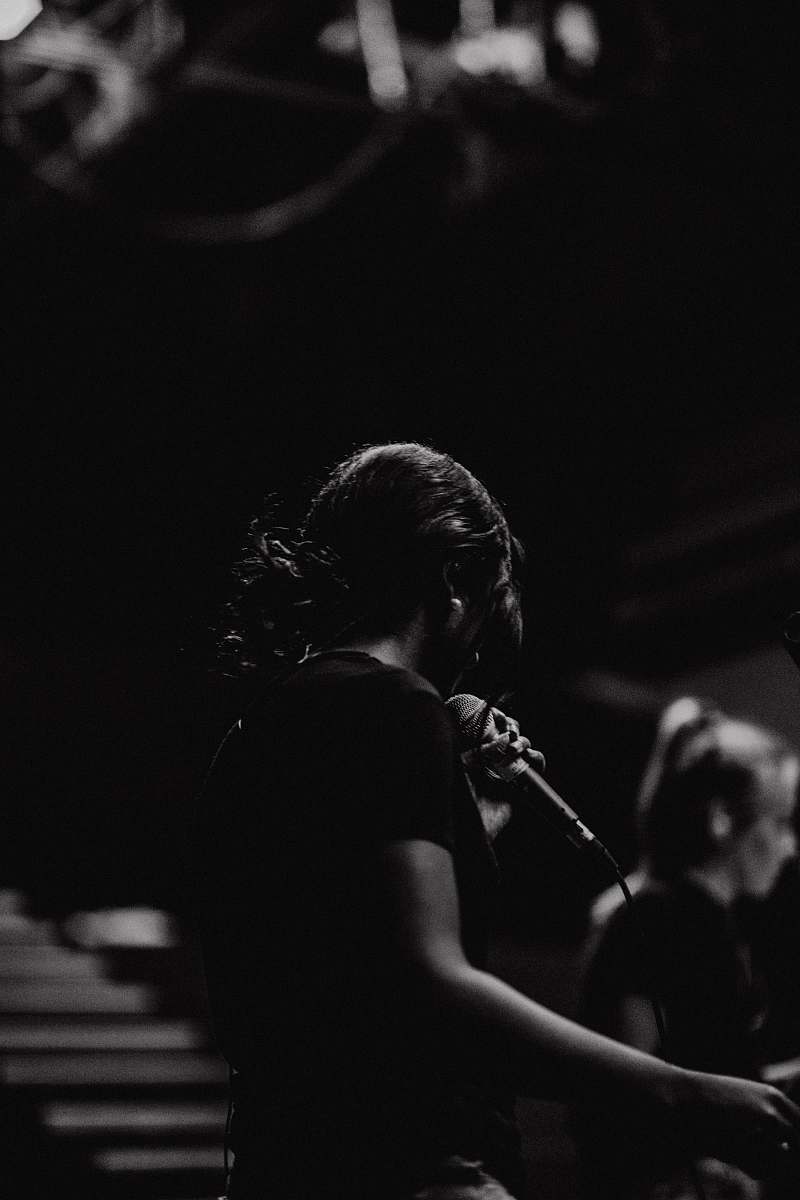 person grayscale photography of person holding microphone human