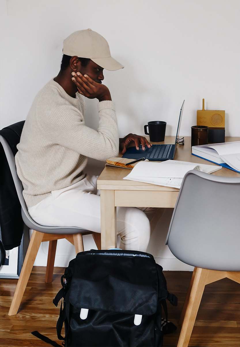 furniture man in white sweater sitting on chair using Microsoft Surface Laptop 3   table