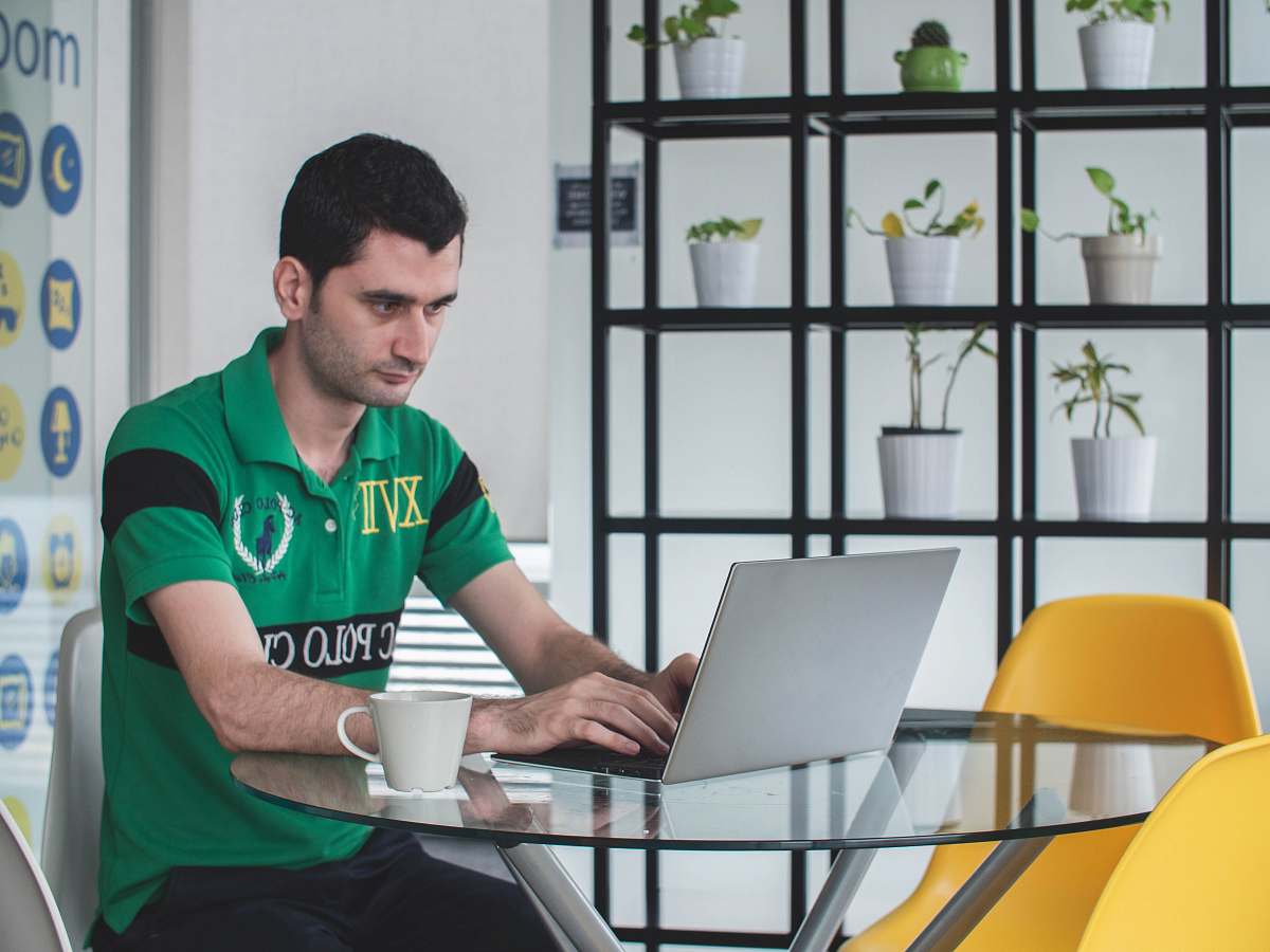 person man sitting on gray metal chair while using gray laptop computer people