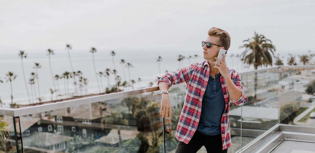 human man in red plaid shirt talking to phone on terrace accessories