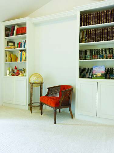 shelf red padded brown wooden armchair beside white wooden shelf bookcase