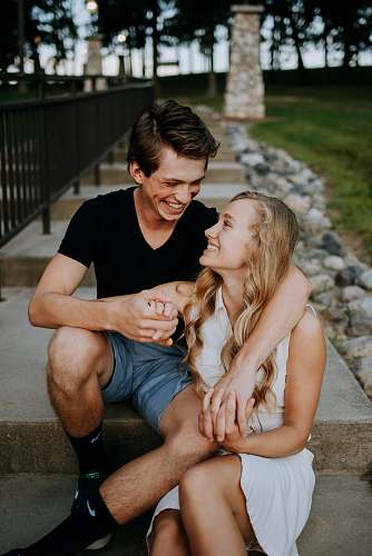 person man holding the hand of a woman while siting on concrete staircase apparel