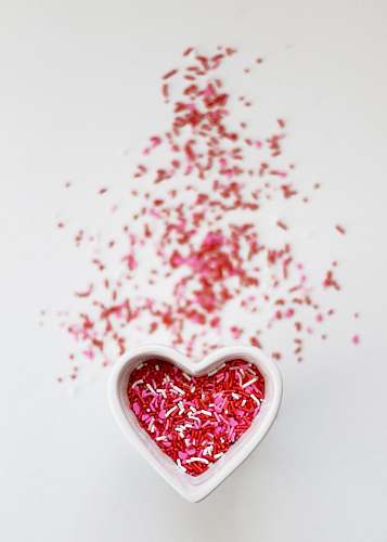 valentine selective focus photo ofsprinkles in heart ceramic bowl candy