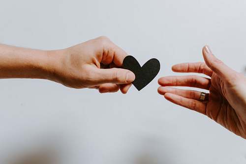 human person reaching black heart cutout paper finger