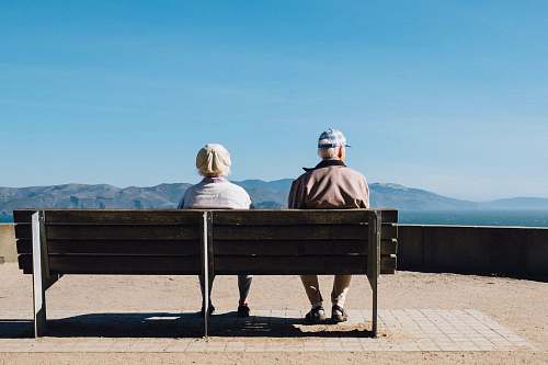 person man and woman sitting on bench facing sea bench