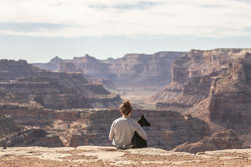 nature person with dog sitting on Grand Canyon cliff canyon