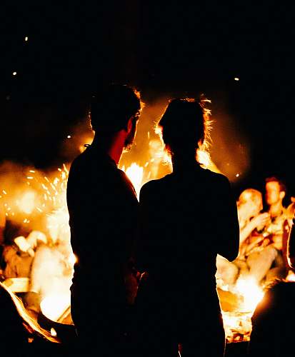fire two persons standing in front of bonfire flame