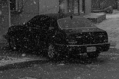 snow black car parked during winter blizzard