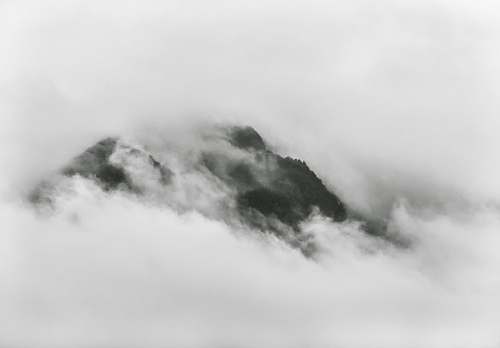 grey photo of mountain covered with mist mountain