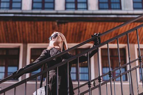 person woman standing on stair while holding rails during daytime railing
