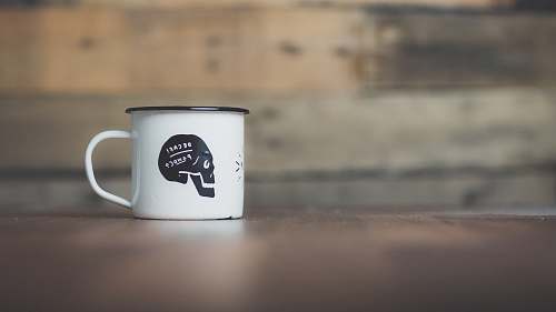 cup white ceramic mug on brown wooden table near gray wall mug