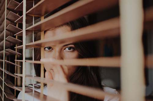 thailand woman peeking over window blinds woman