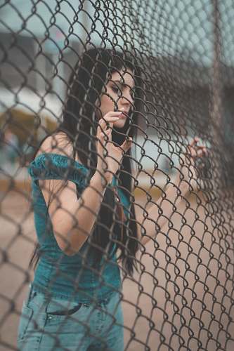 person photography of woman touching gray metal fence people
