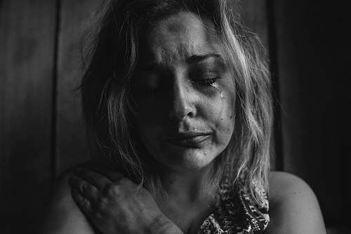 human grayscale photo of woman crying holding her right chest black-and-white