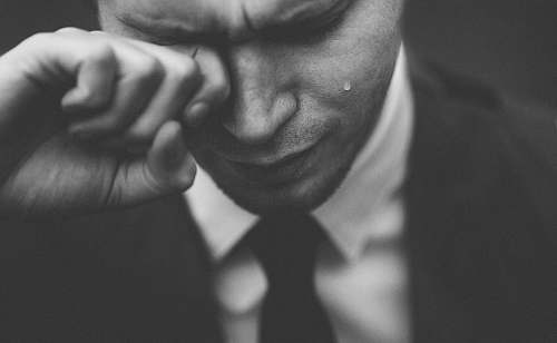 black-and-white man wiping his tears grey