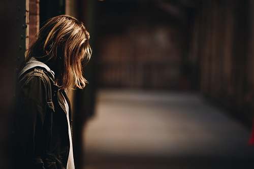 person woman leaning against wall facing down woman