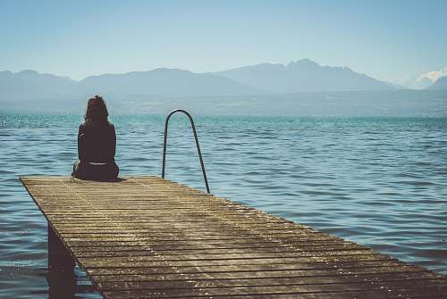 person woman sitting on dock during daytime pier