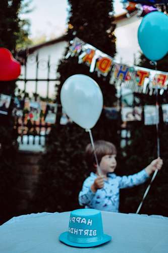 human boy holding blue and white balloons at the party people