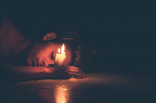 candle lighted candles on man's hand lying on the floor man