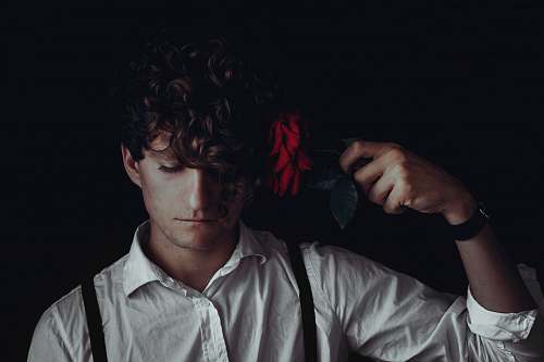human man in white dress shirt holds red flower hair