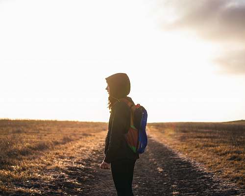 human person wearing backpack standing on pathway during golden hour walking