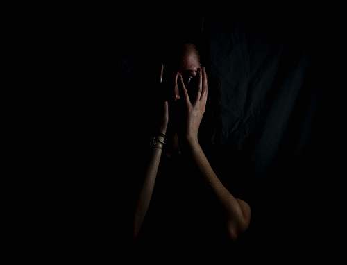 human woman holding her face in dark room woman