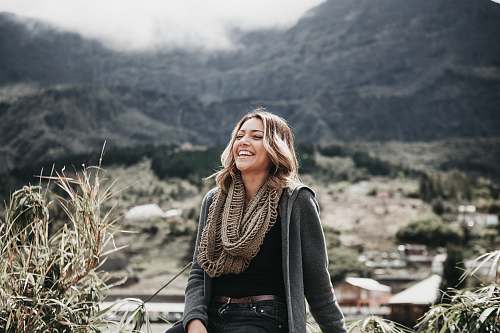 human woman sitting beside grass near mountain range people