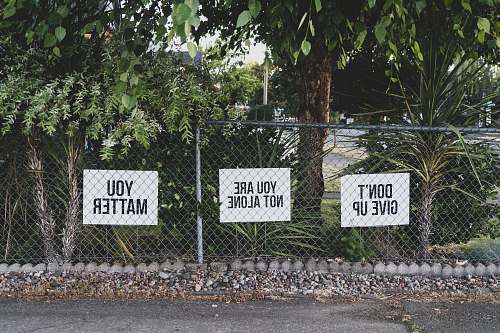 fence don't give up. You are not alone, you matter signage on metal fence 7-11 gas station