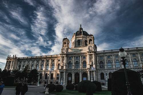 person brown concrete building under blue sky and white clouds during daytime city