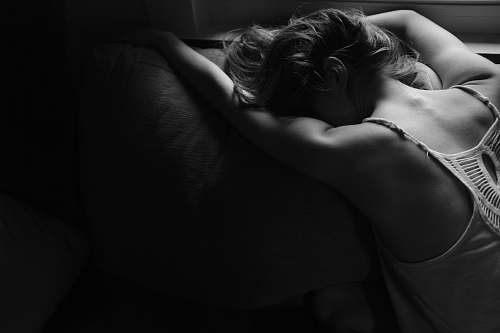 people grayscale photography of woman laying on pillow woman