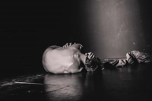 pain grayscale photography of man lying on floor sadness