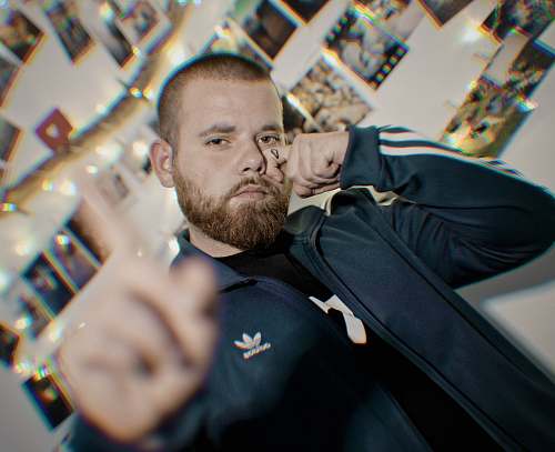 person man wearing adidas hoodie standing beside wall face