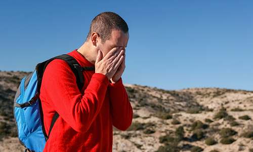 person man wearing red crew-neck sweater with teal and black backpack outdoor during daytime camí dels cartoixans