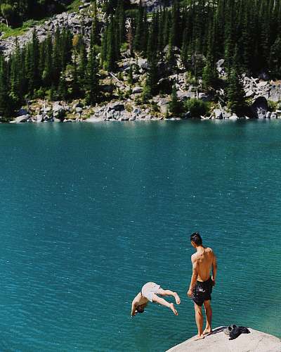  man in black shorts standing on rock near body of water during daytime 