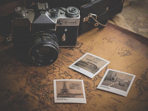 black and grey DSLR camera near several photos on brown map