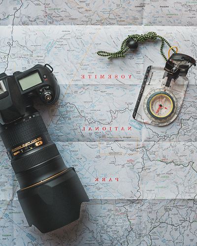 black Nikon DSLR camera beside of map compass