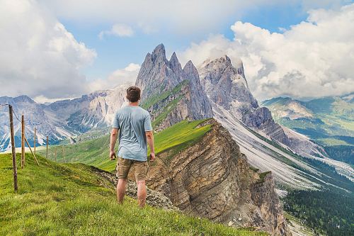 man in blue T-shirt on top of the mountain under the blue sky