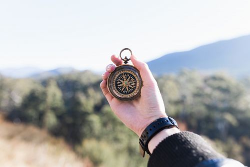 person holding compass selective focus photography